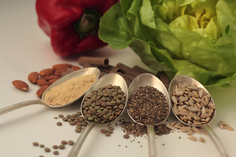 Sample foods from low-GI PCOS (Polycystic Ovary Syndrome) diet. Lentils, maca powder, chia seeds, sunflower seeds, buckwheat pasta, almonds, bell pepper and lettuce.
