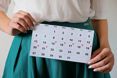 Woman holding calendar with marked menstruation dates. Woman healthcare and gynecology concept.