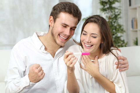 Happy excited couple making positive pregnancy test and celebrating