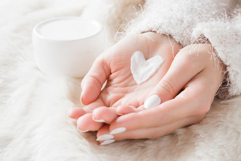 Beautiful groomed woman's hands with cream jar on the fluffy blanket. Moisturizing cream for clean and soft skin in winter time.