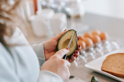 woman cutting avocado during breakfast